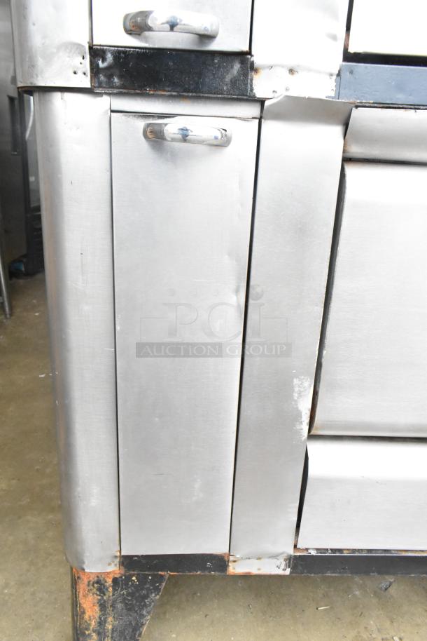 Commercial gas-powered single burner pizza oven with cooking stones, stainless steel, visible wear, dented corners.