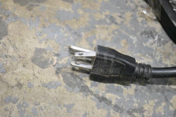 A grounded power plug on a concrete surface, part of the Mahlkonig K30ES/12 Espresso Bean Grinder, 115 Volts, 1 Phase, without lid.