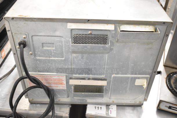 Panasonic NE-17523 commercial countertop microwave back view, 208/240V, used condition, visible power cord and ventilation vents.