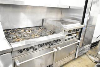 Garland commercial gas range with 6 burners, flat top griddle, 2 ovens, overshelf, and backsplash in used condition.