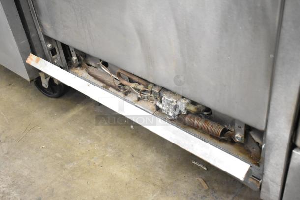 Garland commercial gas range underside with exposed components; visible wear, includes wheels and metal frame detail.