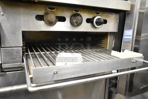 Garland commercial gas-powered 6 burner range with flat top griddle, 2 ovens, over shelf, and backsplash visible.