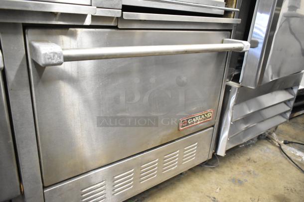 Garland commercial 6 burner range with flat top griddle, dual ovens, over shelf, and backsplash. Stainless steel, used condition.