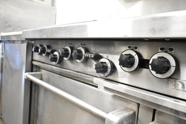Garland commercial gas range with 6 burners, flat top griddle, 2 ovens, over shelf, and backsplash. Good condition.