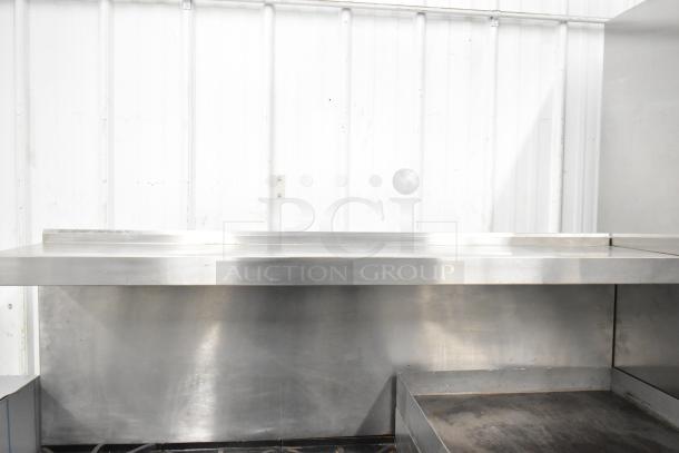 Garland commercial gas range, 6 burners, flat top griddle, 2 ovens, over shelf, and backsplash. Stainless steel finish.