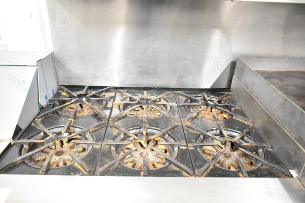 Garland commercial gas range with 6 burners, flat top griddle, 2 ovens, shelf and backsplash. Used condition.