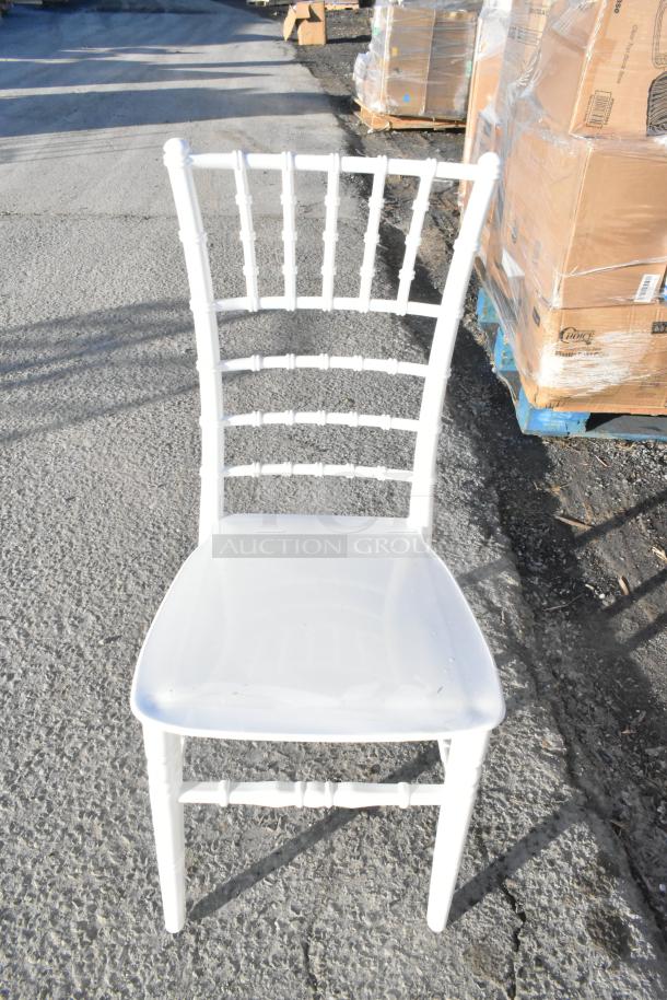 White resin Chiavari chair by Lancaster Table & Seating, scratch and dent condition, seen outdoor on pavement.