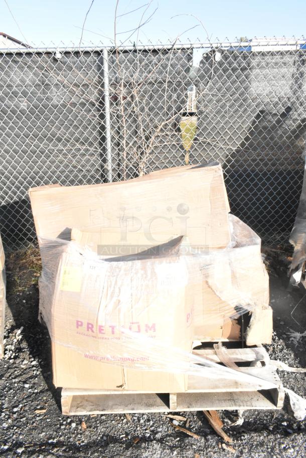 Pallet with boxed items labeled "PRETM" and "FEB26-161," including new scratch and dent stool and seat cushions.