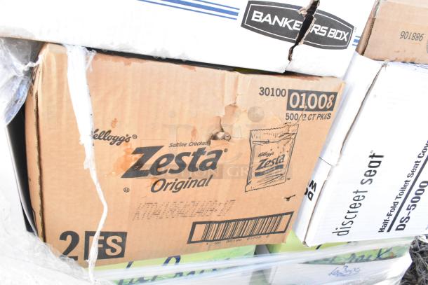 Cardboard box containing Kellogg's Zesta Original saltine crackers, slight damage visible. Multiple similar items packed together.