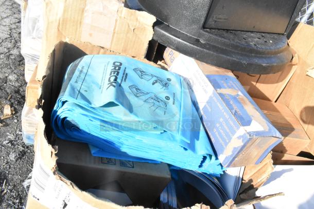 Cardboard box with Oreck vacuum bags and sealed item. Assorted, new condition. Part of a scratch and dent auction lot.