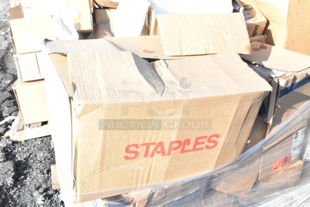 Cardboard box labeled "Staples" amid other boxes. Scratch and dent condition. Contains assorted items like toilet seat covers.