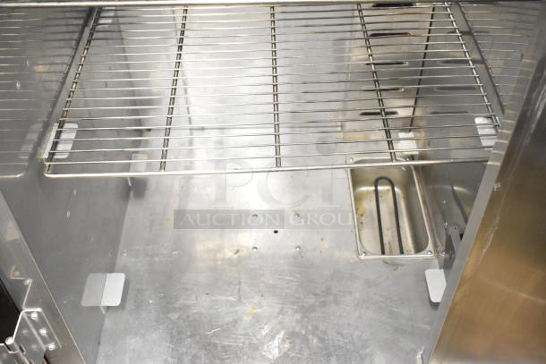 Plate Mate commercial heated holding cabinet interior with metal racks. Includes commercial casters for mobility. Visible wear.