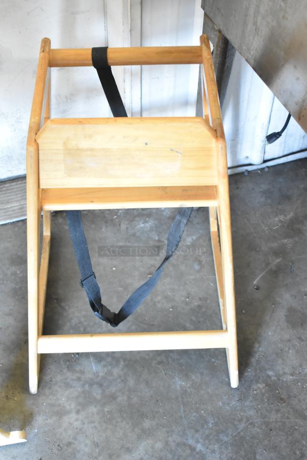 Wooden high chair with a safety strap, shows wear. Bid on three chairs in one lot for added value.