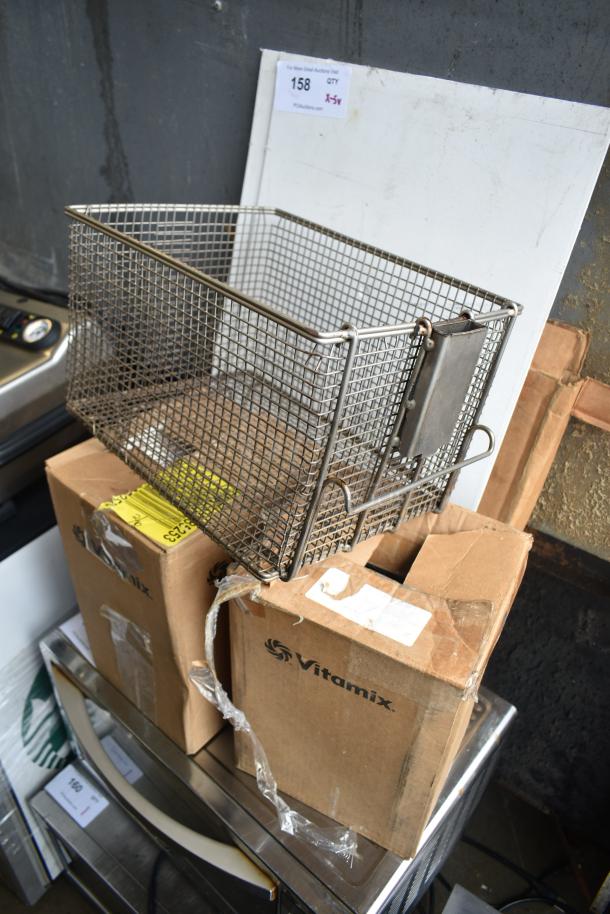 Five-item lot with a pressure fryer basket and multiple Vitamix blender pitchers in original boxes. Auction tag indicates quantity five times bid.