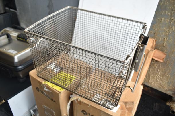 Metal pressure fryer basket on top of boxes labeled "VitaMix," suggesting inclusion of blender pitchers, part of five-item auction.