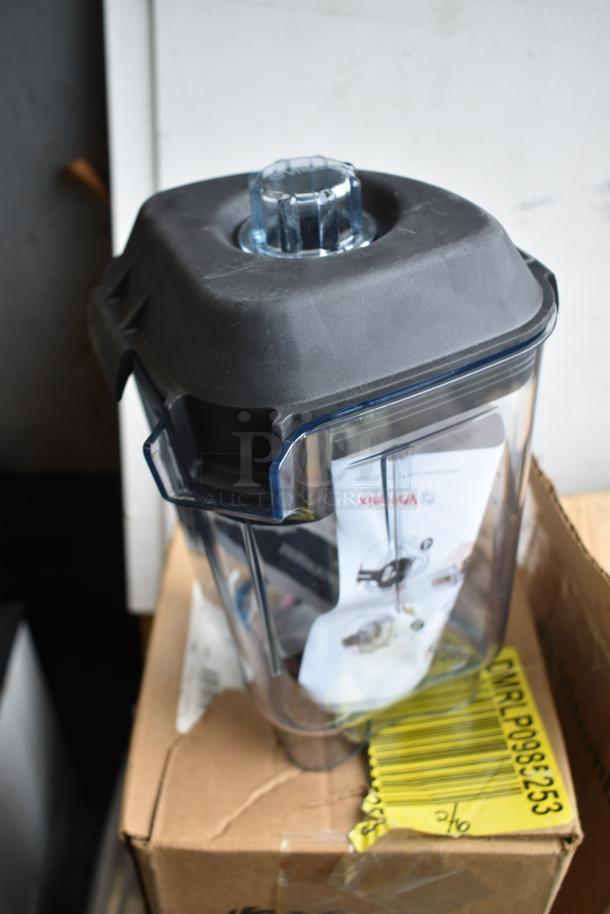 VitaMix blender pitcher with black lid, in good condition, on a box with visible barcode and instructions inside.