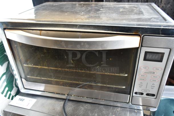 Oster TSSTTVDGXL countertop toaster oven, 120 volts, 1 phase, stainless steel exterior, digital controls, visible wear.