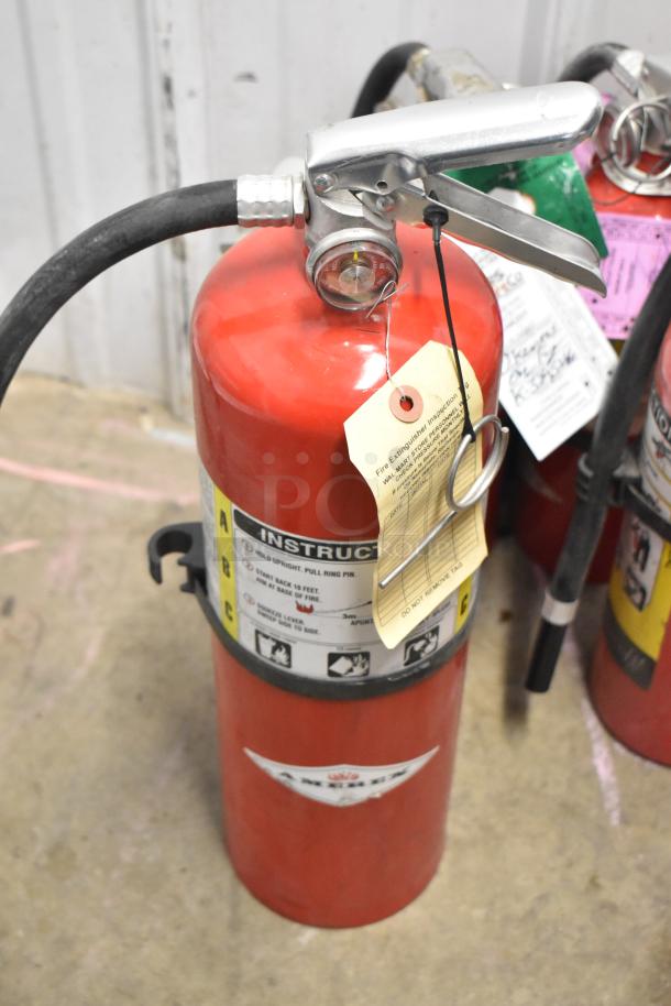 Seven assorted fire extinguishers with inspection tags, featuring instructions and metal handles; buyer pickup only.
