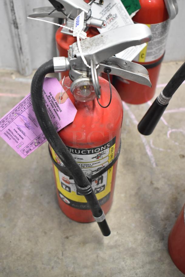 Seven red fire extinguishers with hoses and labels. Includes safety tags. Local pickup only.