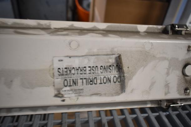 4 light fixtures with worn, dirty surfaces. Label reads "DO NOT DRILL INTO HOUSING USE BRACKETS." Auction for 4 units.