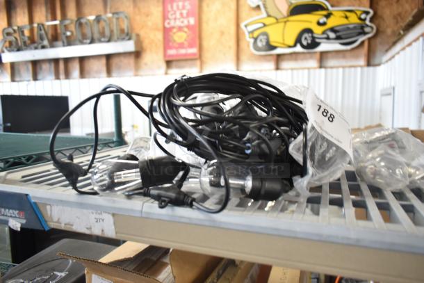 String of lights with black cable and clear bulbs, coiled on a shelf. Tag marked "188." Appears in new condition.