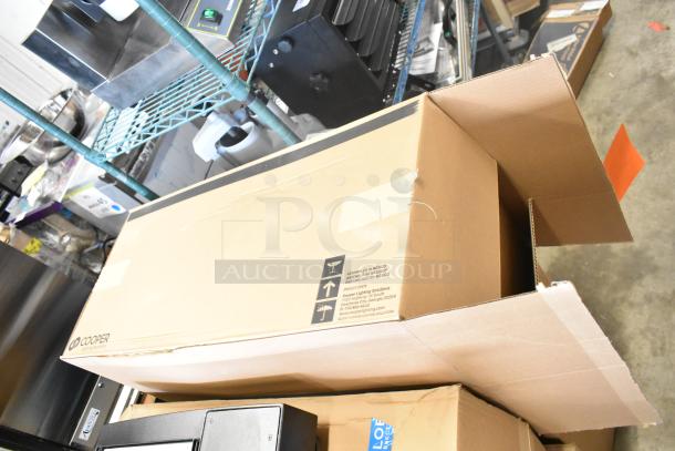 Cardboard box containing brand new Cooper Lighting light fixture. Box shows assembly details and Cooper Lighting branding.