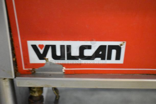 Vulcan commercial floor braising pan, red with logo, showing signs of wear and chipped paint on the surface.