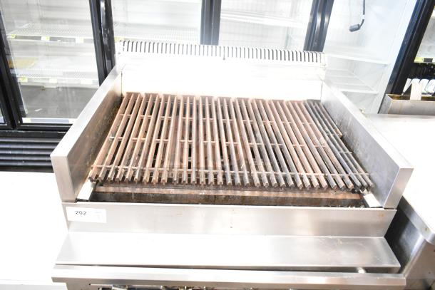 US Range commercial gas-powered charbroiler grill with oven. Features metal grates, stainless steel body, and control knobs. Used condition.