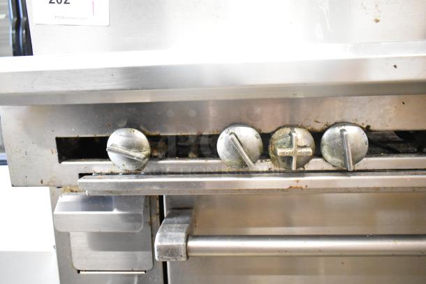 US Range commercial gas charbroiler grill with oven, showing front knobs. Worn condition, auction tag visible.