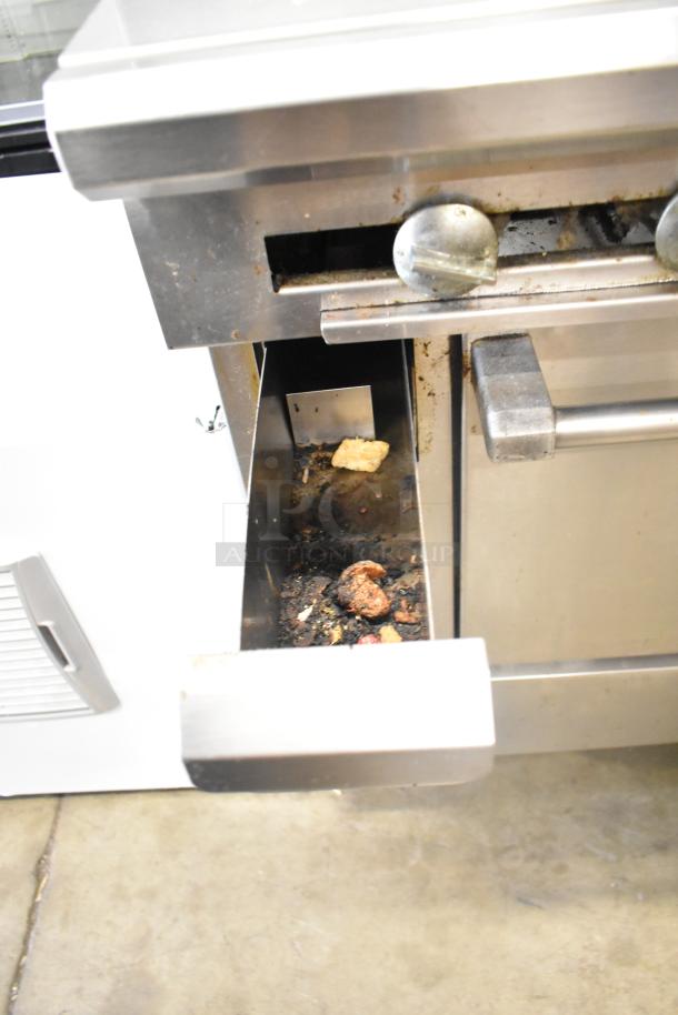 US Range Commercial Gas Charbroiler Grill with oven, showing open drip tray with debris, stainless steel construction.