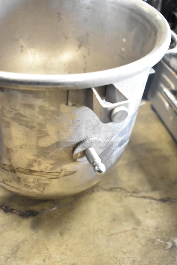 Set of commercial mixing bowls and paddle attachments, showing used condition. Durable metal construction, suited for heavy-duty kitchen tasks.