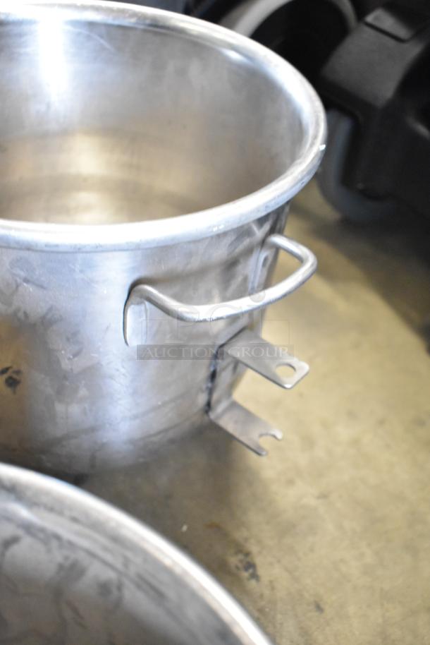 Two commercial mixing bowls with metal handles, showing signs of wear, part of auction lot with paddle attachments.