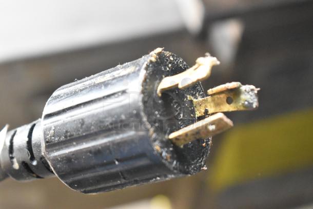 Close-up of a black electrical plug with visible wear and three prongs.