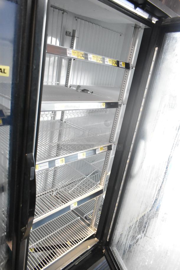 2017 True GDM-72F-HC three-door commercial freezer with glass doors, empty shelves. Model and price tags visible.