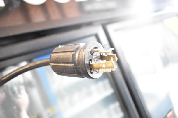 Close-up of the power plug for the 2017 True GDM-72F-HC 3 Door Reach In Freezer Merchandiser, showing its prongs and cord.