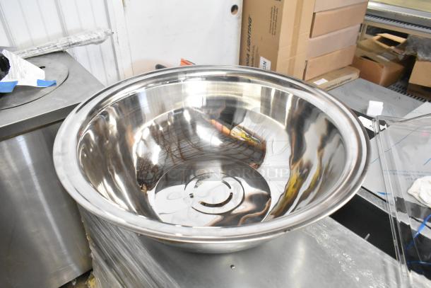 Brand new metal bowl with reflective finish, slight scratches, paired with a clear poly lid, ideal for kitchen use.