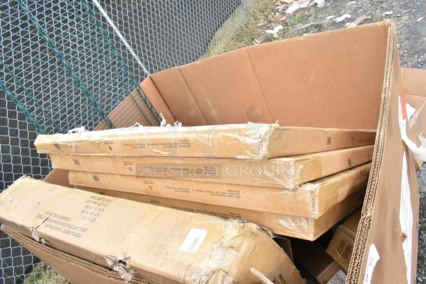 17 brand new scratch and dent items including table base pieces and a waitress stand in cardboard packaging.