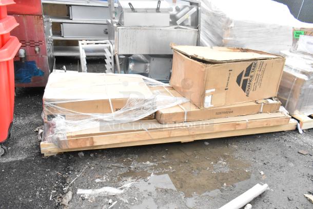 Four boxed, new scratch and dent items on a pallet, including trash can cabinet and shelf kit, marked "Advance Tabco."