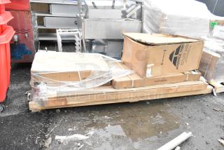 Four boxed, new scratch and dent items on a pallet, including trash can cabinet and shelf kit, marked "Advance Tabco."