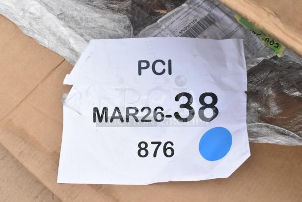 Cardboard box with visible PCI tag showing "MAR26-38" and "876," partially wrapped in shipping material.