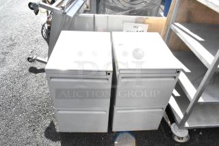 Two gray metal two-drawer filing cabinets, pre-owned, with minor wear, ideal for office storage.
