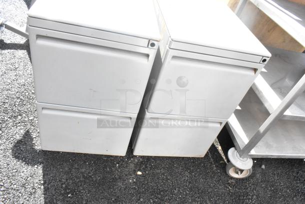 Two gray metal 2-drawer filing cabinets, slight wear, durable construction, ideal for office storage.