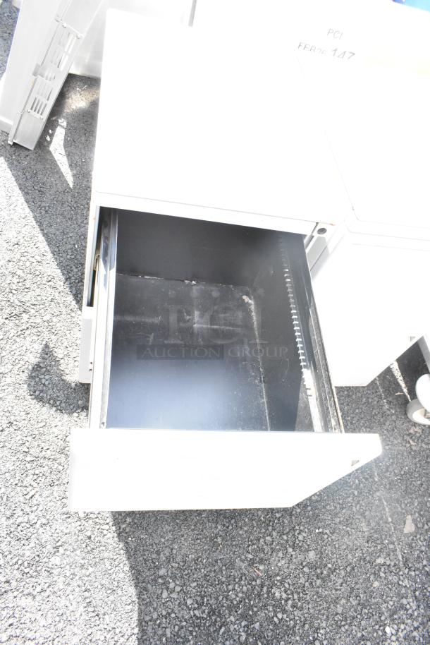 Gray metal 2-drawer filing cabinet, open drawer view. Sturdy construction, ideal for office use. Light wear visible.