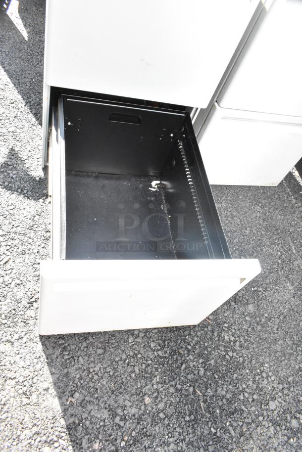 Gray metal 2-drawer filing cabinet, open drawer view. Used condition, sturdy metal construction, slight surface wear.