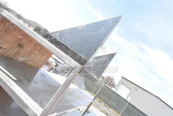 Commercial 7-tier metal shelving unit with contents on commercial casters; used and in a warehouse setting.