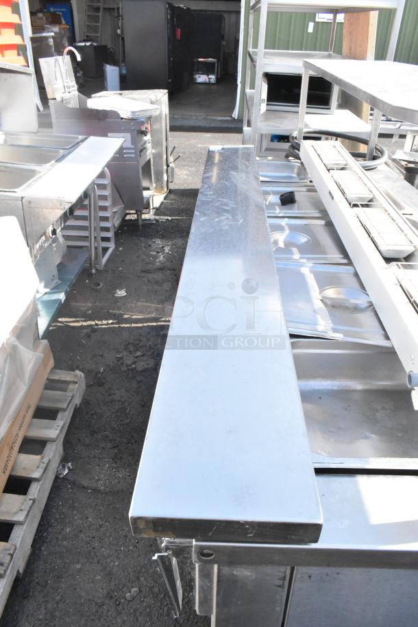 Stainless steel metal shelf in used condition, reflective surface, sturdy construction, and rectangular shape.