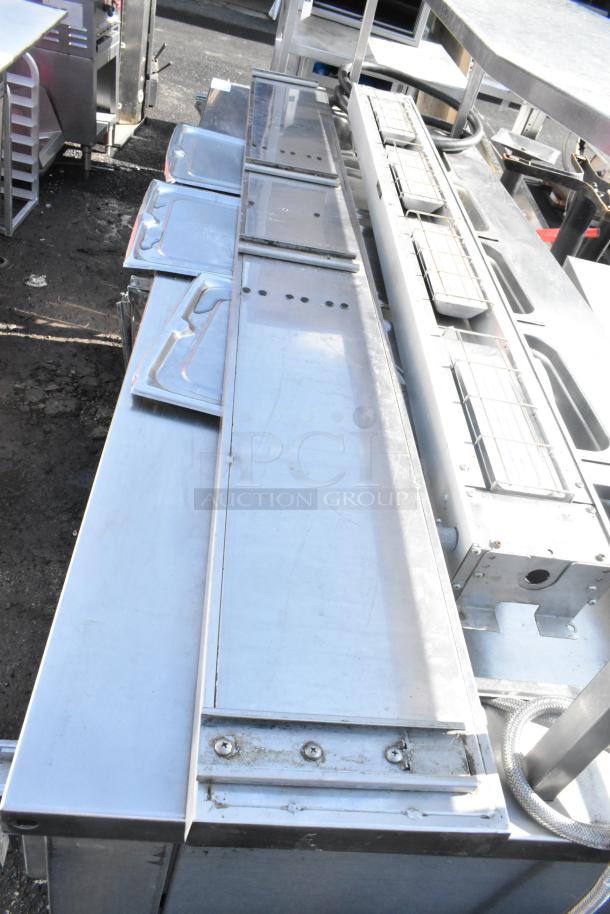 Industrial metal shelf with multiple compartments, stainless steel finish, visible screws, in used condition.