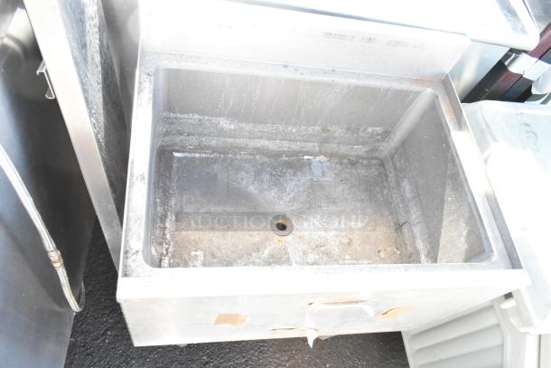 Commercial ice bin, metal construction, drain at center, visibly used with some wear. No visible branding or labels.