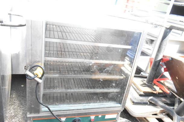 Commercial heated holding cabinet merchandiser with multiple shelves, visible power cord, on commercial casters.