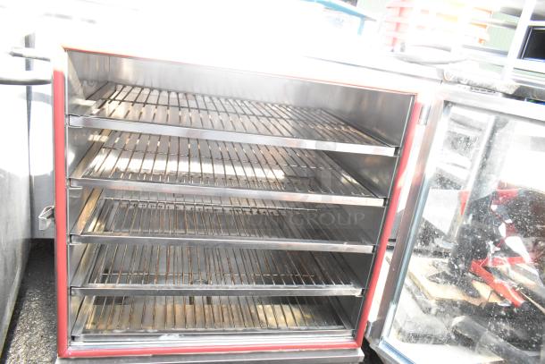 Commercial heated holding cabinet with multiple wire shelves, stainless steel interior, on commercial casters.